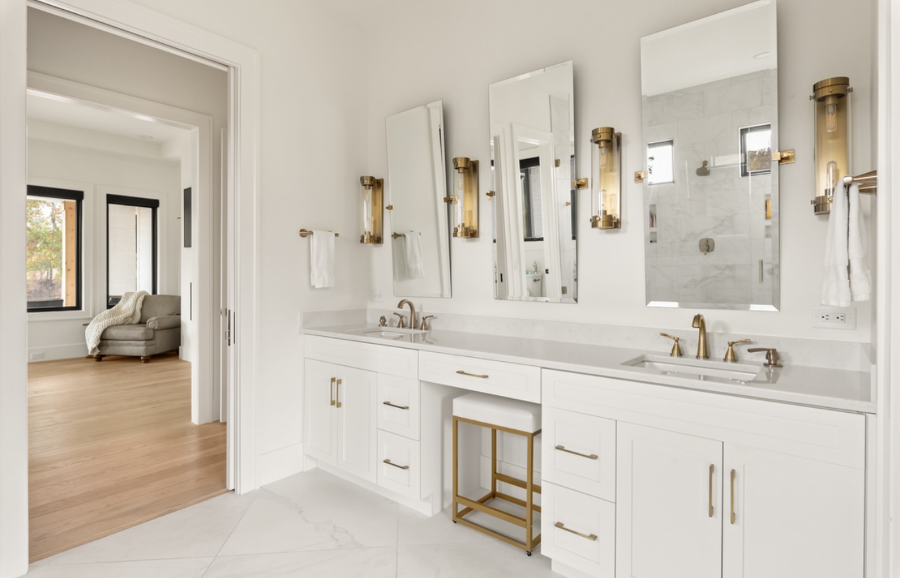 Primary bathroom double vanity with brass sconces and mirrors