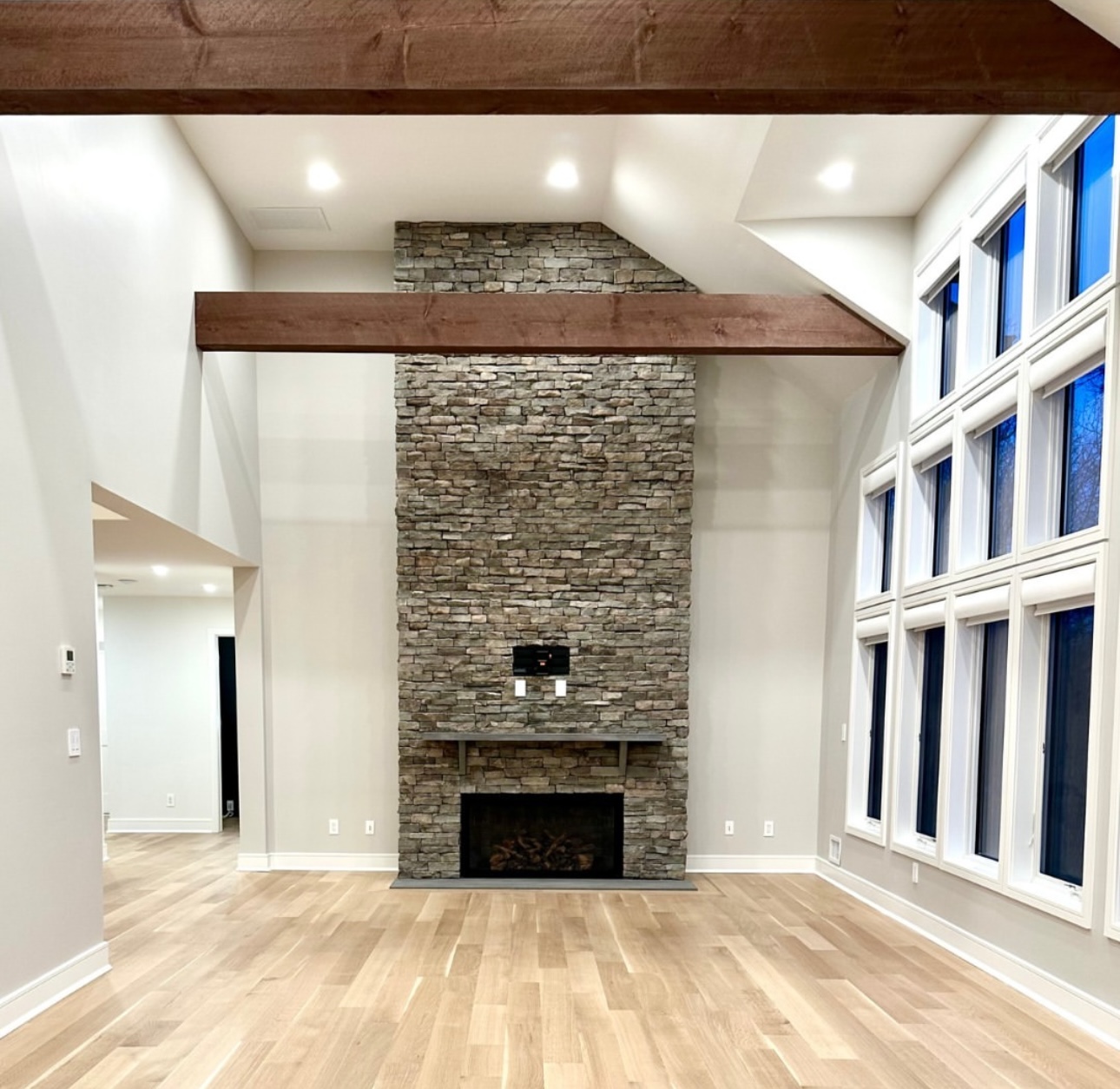 Great room with stacked stone fireplace and exposed wood beams