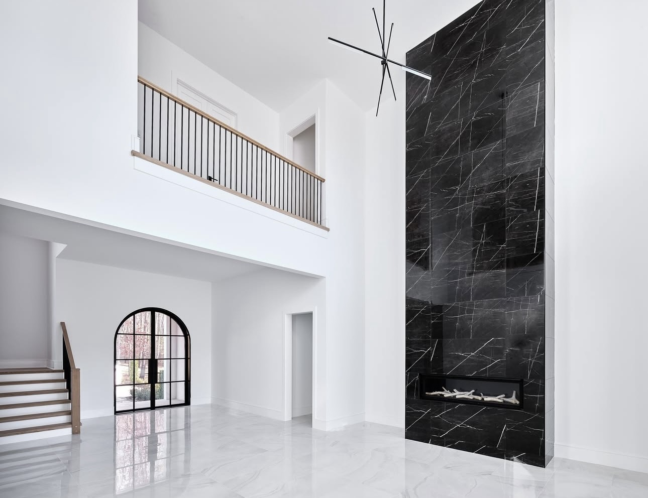 Two-story foyer with a black marble fireplace feature wall