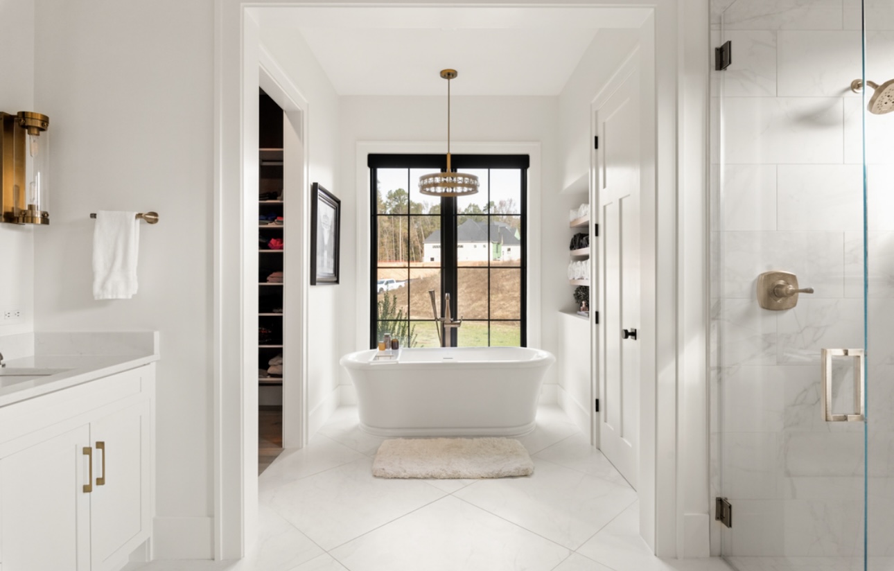 Primary bathroom with freestanding tub and view into a walk-in closet